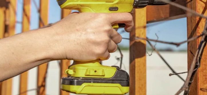 A person drilling pilot holes to install a pet grille on a swinging screen door