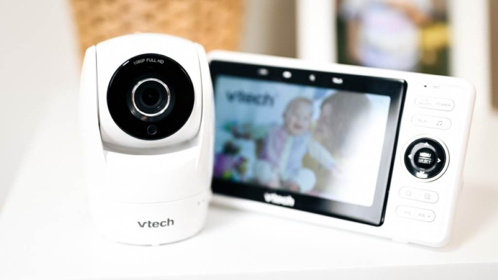 Parent holding the 5-inch handheld screen of VTech VM901 showing sharp night vision of sleeping baby