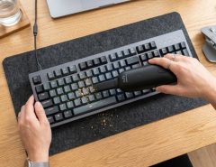 Person using a mini vacuum to clean a mechanical keyboard.